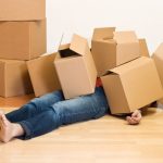Man laying down covered with moving boxes