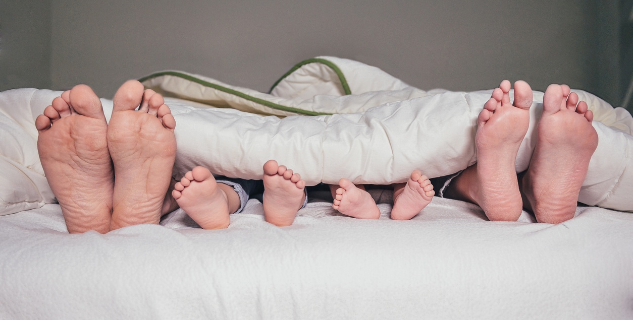 Row of family feet show out of bed sheets