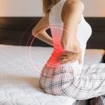 Female suffering from back pain because of uncomfortable mattress