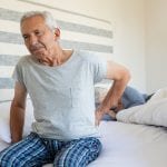 Elderly man suffering backpain from his bed.