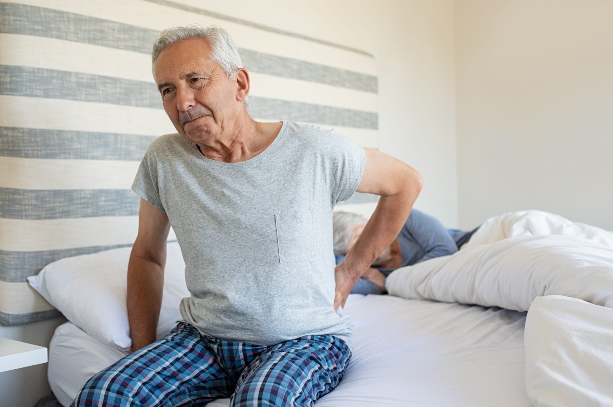 Elderly man suffering backpain from his bed.