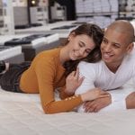 man and woman laying on mattress in mattress store