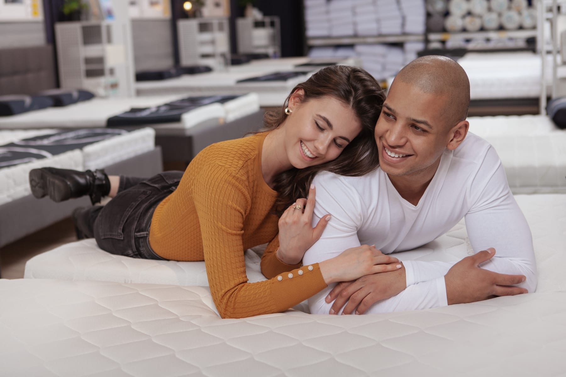 man and woman laying on mattress in mattress store