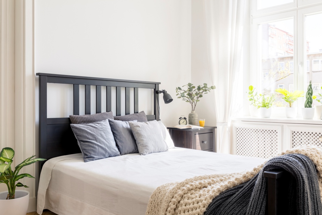 Bed in small room that is well lit with sunlight