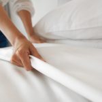 Women making up bed sheets on bed