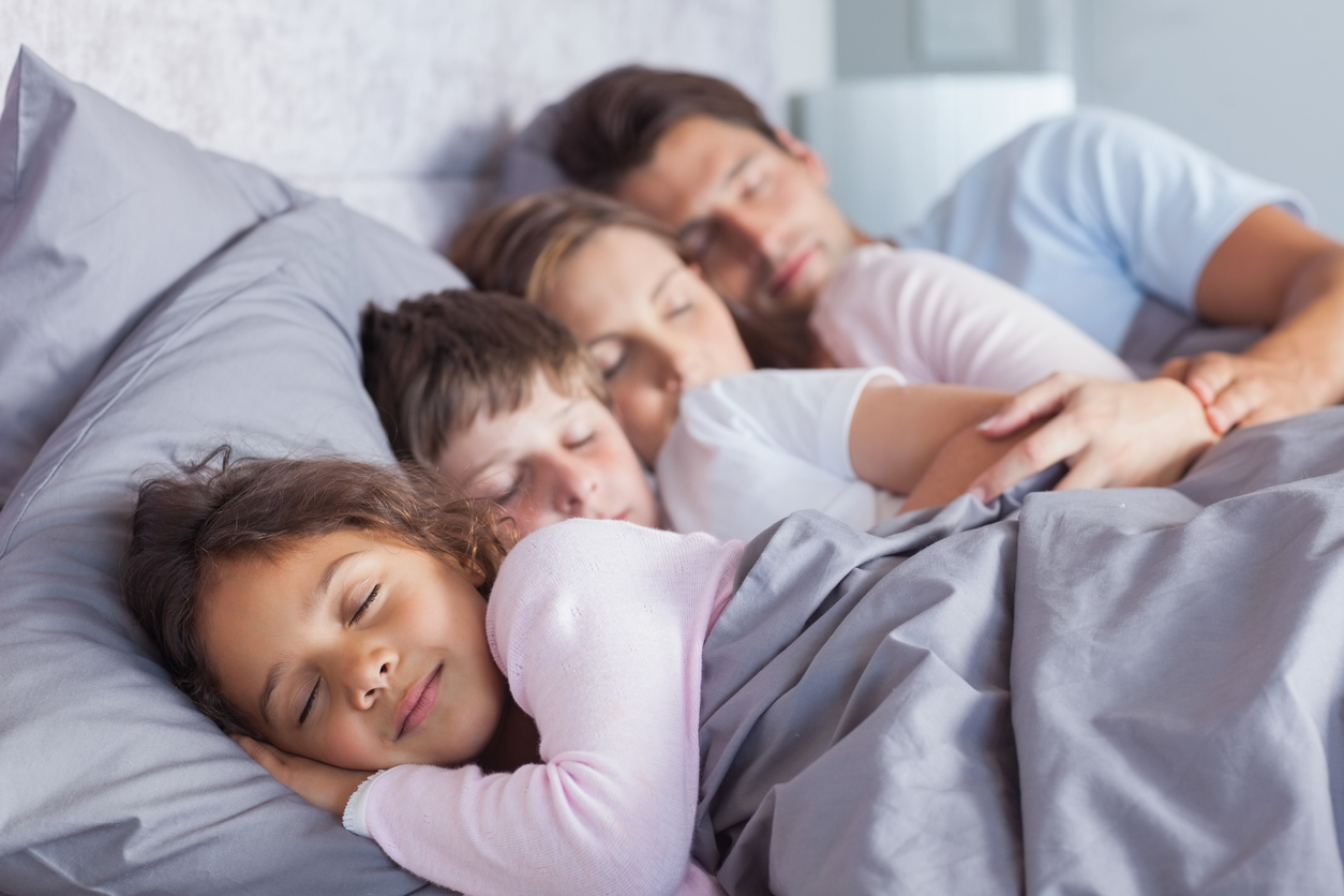 Family sleeping soundly in bed