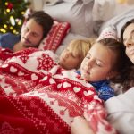 Family sleeping in bed during Christmas season