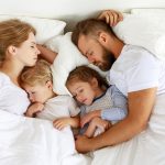 Young family sleeping comfortably in parent's bed
