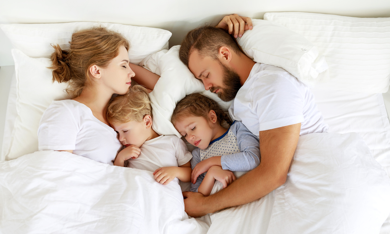 Young family sleeping comfortably in parent's bed