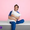 Man sitting on Purple Premier 3 and holding a Purple Pillow