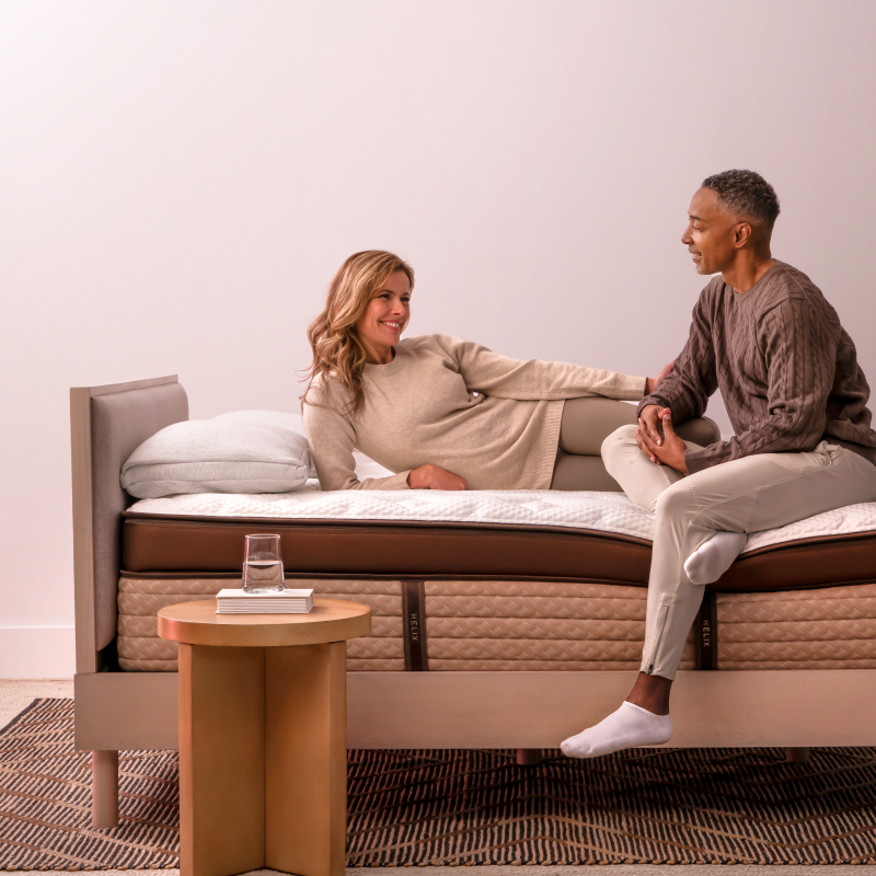 Helix Midnight Elite - Woman side laying and man sitting on mattress